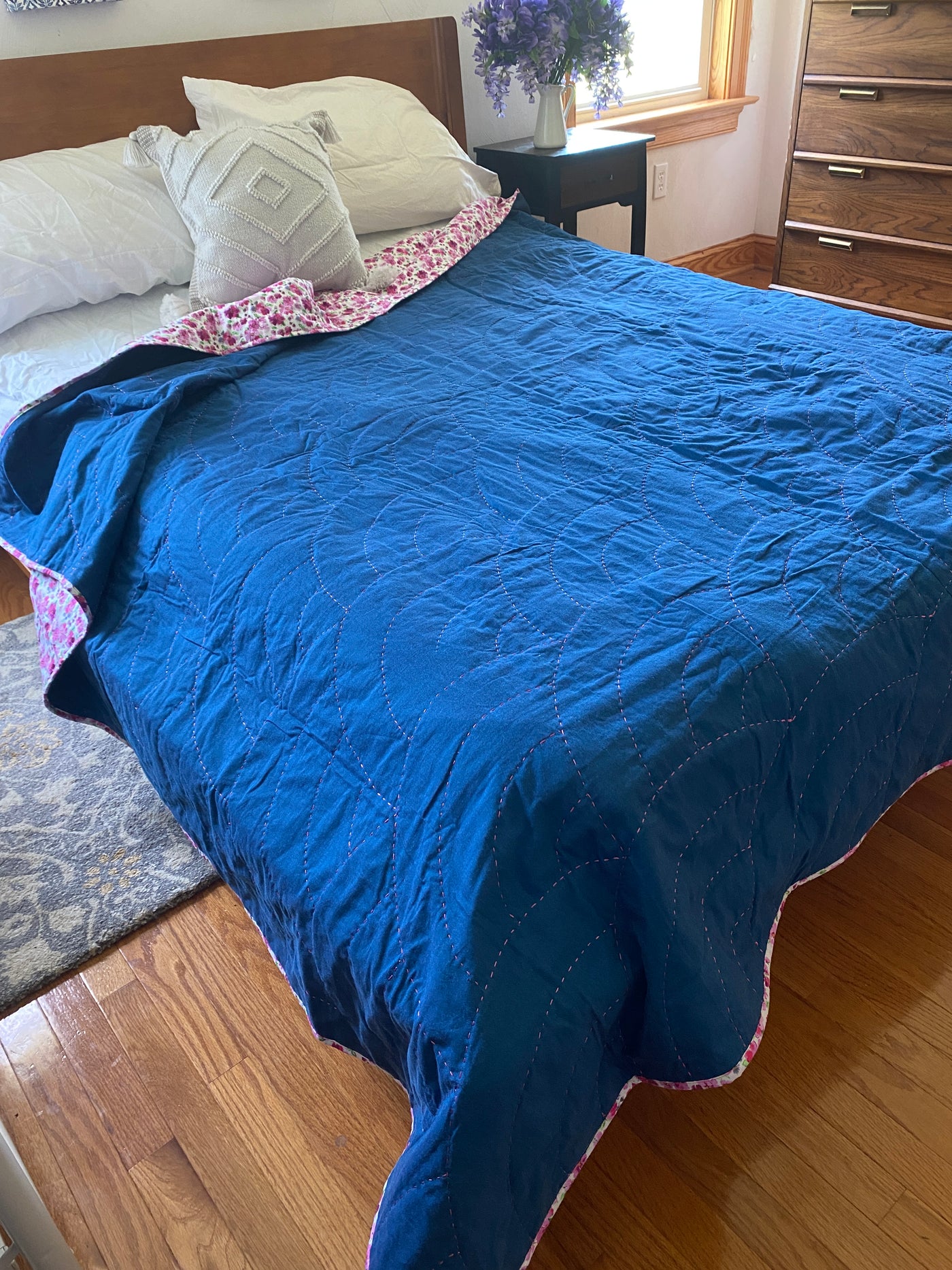 Hope quilt is a whole cloth of dark indigo fabric with a pink and white floral backing. I used a shinny rayon, magenta thread to create arches (aka Baptist Fans) all over the quilt.