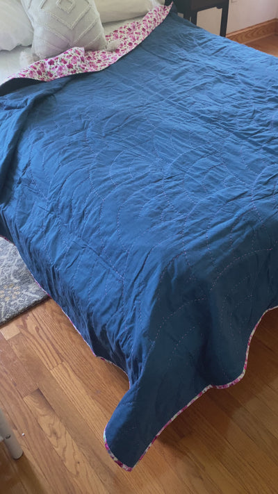 A video of Hope quilt, a whole cloth of dark indigo fabric with a pink and white floral backing. I used a shinny rayon, magenta thread to create arches (aka Baptist Fans) all over the quilt.