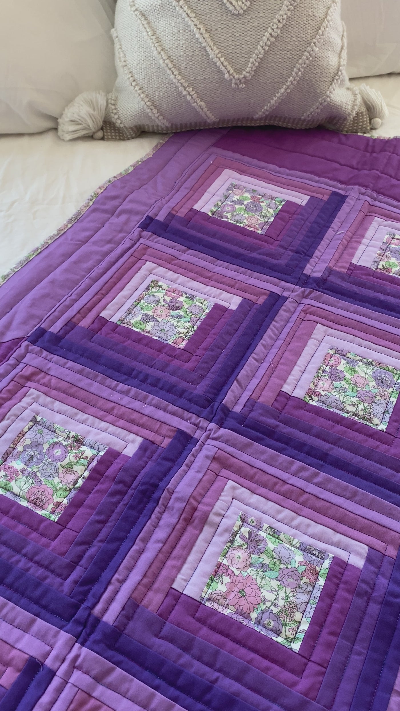 A video of the details of this "Cabin in the Garden- purple" lap quilt.. This heirloom lap quilt with a log cabin pattern with shades of lavenders and purples and a small print floral cover the front of this quilt. The binding and backing match the center floral print. It is made with a warm, heavy weight cotton/wool blend batting inside.