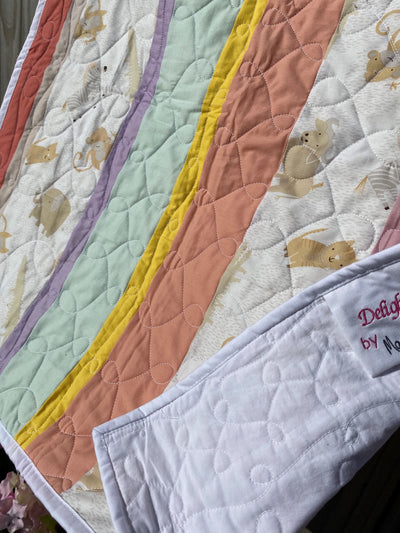 100% Organic Cotton, handmade, heirloom, patchwork, soft pastels, yellow, peach, sea, purple, and white background baby animal fabric, with a white backing, crib size, swirl and loop top quilting, machine top stitched binding, on this sweet girl, boy, or gender neutral crib quilt with a signed embroidered tag