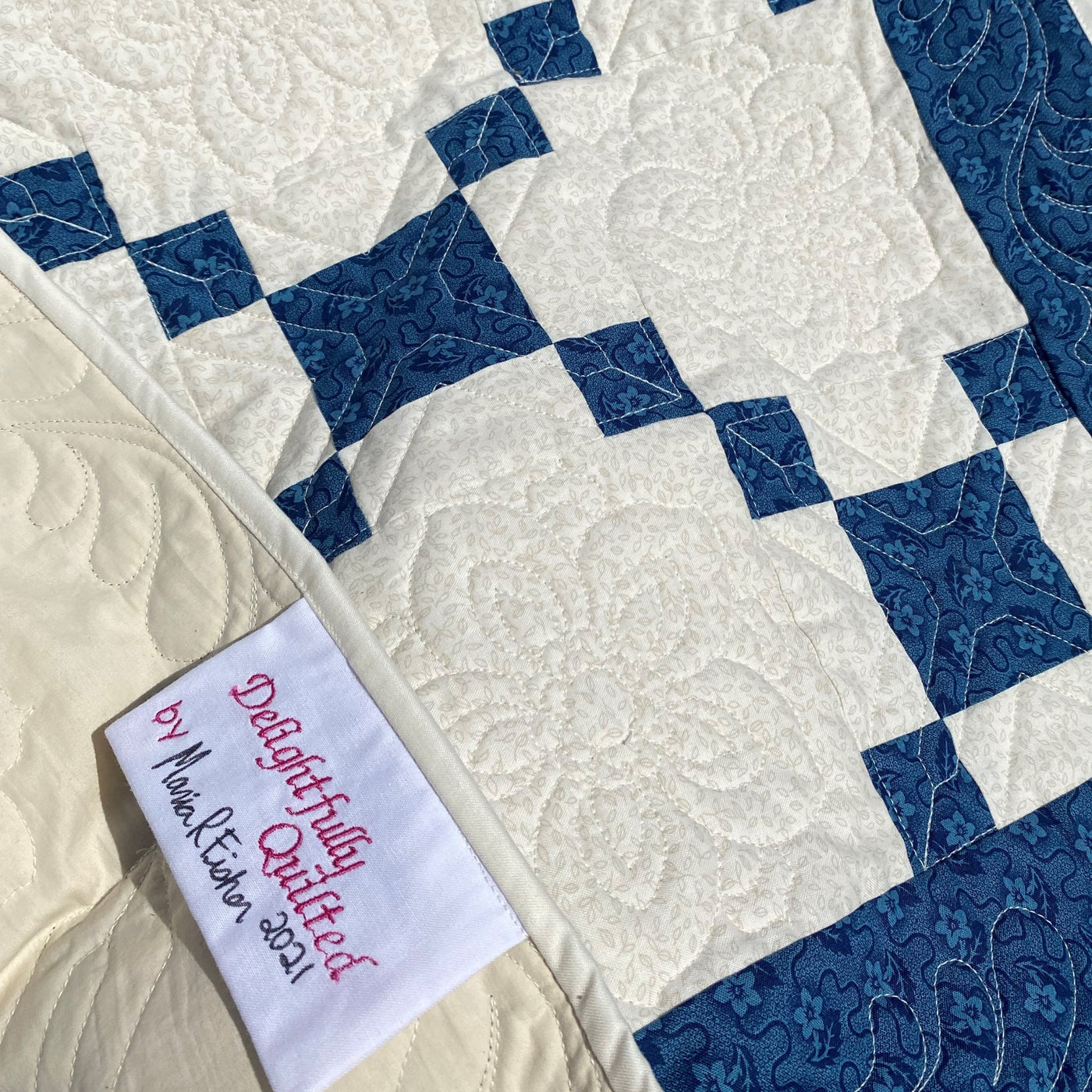 a handmade, heirloom, patchwork of indigo/blue nine patch with white background fabric, natural color backing, 100% cotton batting, Floral top quilting in the white centers, X's in the 9 patch squares, and feathers along the borders, machine top stitched binding, on this baby size quilt