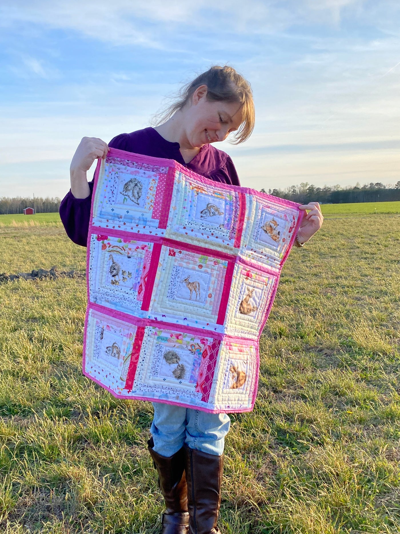 A scrappy or multiple fabrics in pink and white colors  with baby animal print centers. It is a handmade, patchwork, log cabin style crib or baby quilt